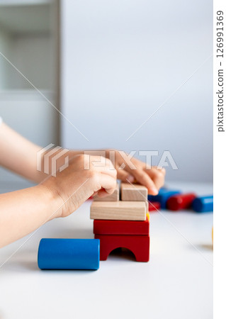 Child building colorful wooden blocks on white table 126991369