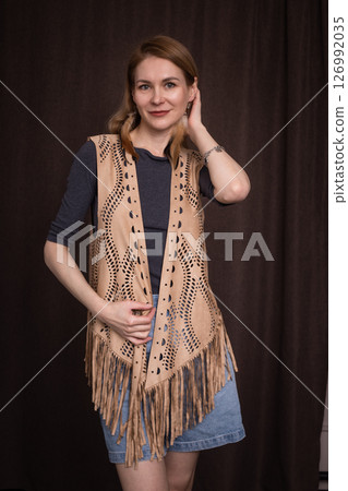 A young girl poses in a boho style suede vest. 126992035