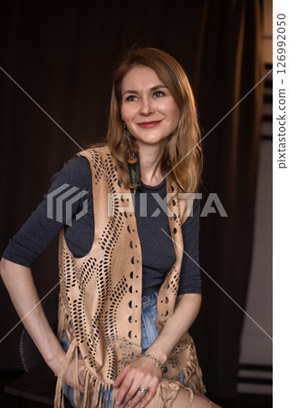 A young girl poses in a boho style suede vest. 126992050