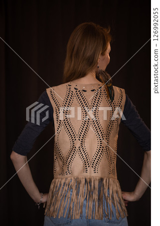 A young girl poses in a boho style suede vest. 126992055
