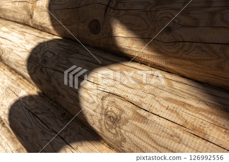 Close-up of a wooden log wall surface with sunlight 126992556