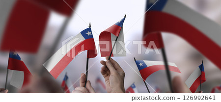 Chile flags in their hands on a blurred urban background 126992641