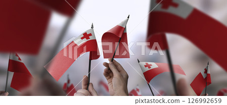Tonga flags in their hands on a blurred urban background Tonga flags in their hands on a blurred urban background 126992659