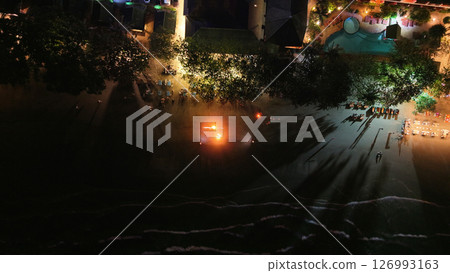 Tourists enjoying fire show on beach at night in tropical resort Tourists enjoying fire show on beach at night in tropical resort 126993163