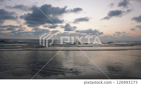 Gentle waves washing ashore during a beautiful sunset at the beach Gentle waves washing ashore during a beautiful sunset at the beach 126993173