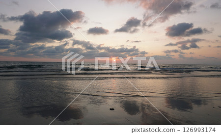 Gentle waves washing ashore during a beautiful sunset at the beach Gentle waves washing ashore during a beautiful sunset at the beach 126993174