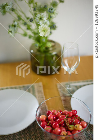 a bouquet of daisies in a glass vase stands on a table on a white background, a wine glass, a wine glass, plate with ripe cherries, table setting, plates, defocus, macrophotography, bokeh 126993249