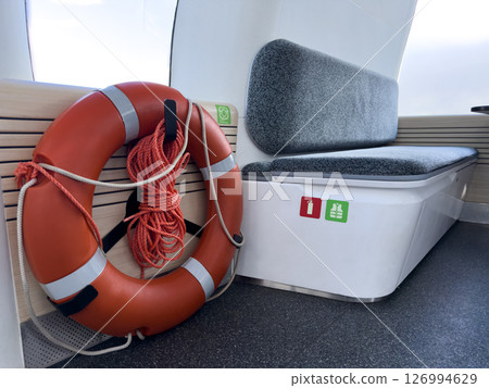 Safety equipment inside electric passenger boat including lifebuoy and seating with fire extinguisher and life jacket icons. Clean modern interior for public water transport. 126994629