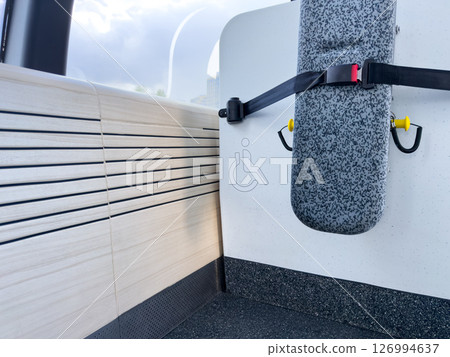 Minimalist view of a folded seat with a safety belt and wheelchair symbol in a modern public transport cabin. Clear visual indicator for accessibility and inclusive infrastructure design Minimalist view of a folded seat with a safety belt and wheelchair symbol in a modern public transport cabin. Clear visual indicator for accessibility and inclusive infrastructure design 126994637