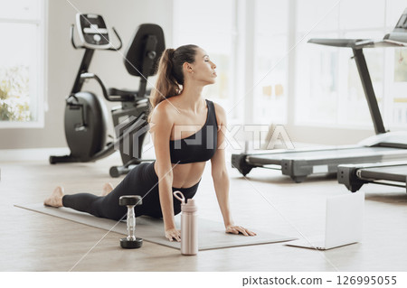 Healthcare Online Training. Young Woman Exercising at Sport club, Watching Video Tutorial on Laptop 126995055