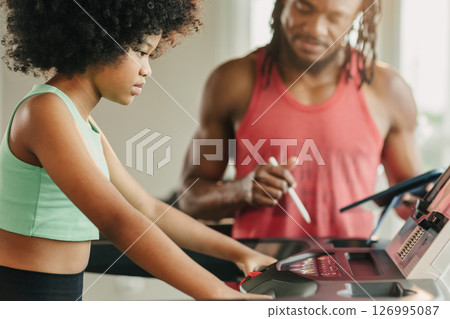 African black girl preteen athlete kid training sport activity with trainer man on treadmill in gym 126995087