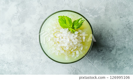 Top view of a lime daiquiri cocktail with crushed ice and basil leaves on a light textured background 126995106