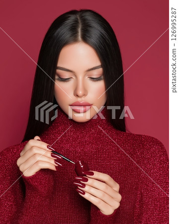 Elegant Woman Decorating Long Nails in Professional Beauty Studio Setting 126995287