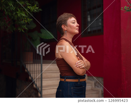 Woman walking narrow streets of old town Antalya during warm summer evening. Historic atmosphere and Mediterranean charm creates peaceful travel experience. near red building 126995423
