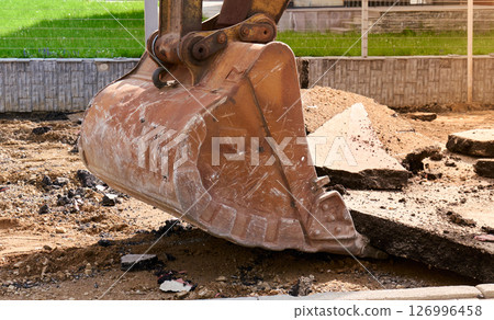 Heavy machinery lifts broken pavement at a residential area 126996458