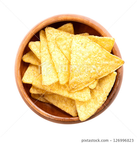 Tortilla chips in a wooden bowl. Classic, crunchy snack food, made from corn tortillas, cut into triangle shaped wedges, fried in oil, and slightly salted. Close-up, from above, isolated, food photo. 126996823