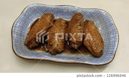 close up of four Taiwanese braised soy sauce chicken wings on a blue and white plate 126996846