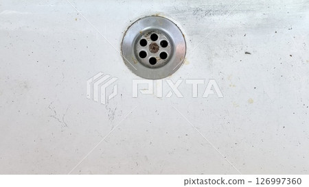 Water drain on a white surface showing signs of wear and dirt 126997360