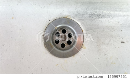 Drain opening in a sink with rust and dirt at a kitchen location Drain opening in a sink with rust and dirt at a kitchen location 126997361