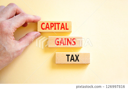 Capital gains tax symbol. Concept words Capital gains tax on beautiful wooden block. Businessman's hand. Beautiful white background. Business and capital gains tax concept. Copy space. 126997816