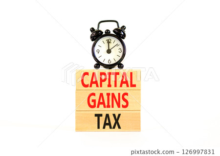 Capital gains tax symbol. Concept words Capital gains tax on beautiful wooden block. Black alarm clock. Beautiful white background. Business and capital gains tax concept. Copy space. 126997831