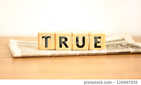 True symbol. Concept word True on beautiful wooden blocks on newspaper. Beautiful wooden table white background. Business, lifestyle, support and true concept. Copy space. 126997856