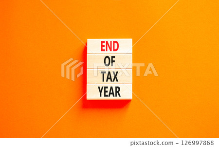 End of tax year symbol. Concept words phrase End of tax year on beautiful wooden blocks. Beautiful orange paper background. Business End of tax year concept. Copy space. 126997868