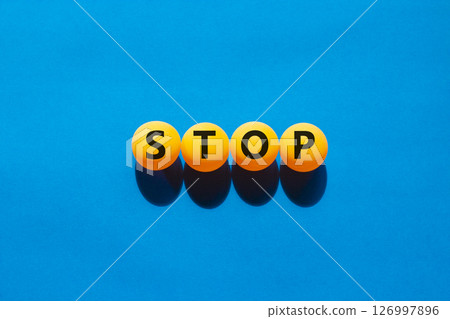 Stop symbol. Concept word Stop on beautiful yellow ping pong balls. Beautiful blue table blue background. Business, lifestyle, support and stop concept. Copy space. Stop symbol. Concept word Stop on beautiful yellow ping pong balls. Beautiful blue table blue background. Business, lifestyle, support and stop concept. Copy space. 126997896