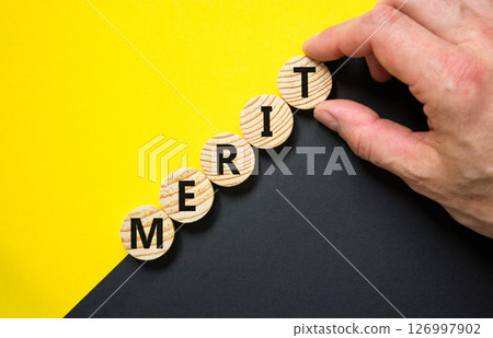Merit symbol. Concept word Merit on beautiful wooden circles. Beautiful yellow and black background. Businessman hand. Business lifestyle merit concept. Copy space. Merit symbol. Concept word Merit on beautiful wooden circles. Beautiful yellow and black background. Businessman hand. Business lifestyle merit concept. Copy space. 126997902