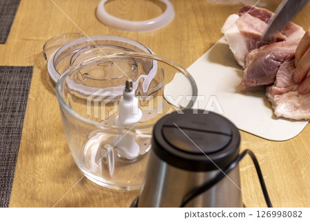 Woman cuts the meat, prepares it to grind it in electrical chopper 126998082
