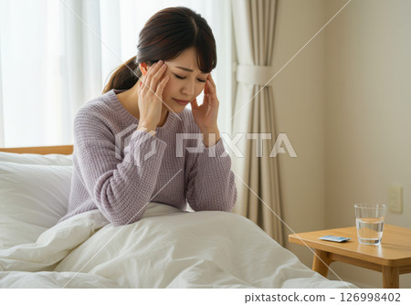 A woman resting in bed with a headache and holding her temples (AI-generated image) 126998402