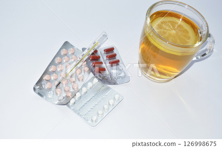 pills, thermometer and tea with lemon on white background pills, thermometer and tea with lemon on white background 126998675