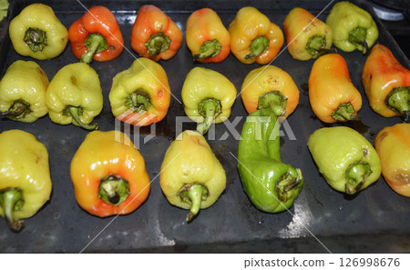 ripe bell peppers laid out on a baking sheet and ready to be baked in the oven ripe bell peppers laid out on a baking sheet and ready to be baked in the oven 126998676