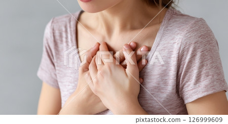 Woman suffering from chest pain holding chest area showing symptoms of heart or health issue 126999609