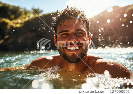 Man enjoying a refreshing swim in a sunlit lake with a joyful expression amidst splashes of water and greenery on a clear summer day 127000001