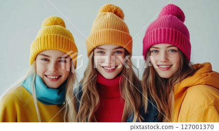 Friends enjoying a winter day indoors wearing colorful hats and cozy sweaters in a bright, cheerful atmosphere with smiles and laughter 127001370