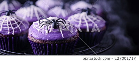 Halloween cupcakes with purple frosting and spider decoration, festive dessert on a wire rack. spooky and seasonal vibes concept 127001717