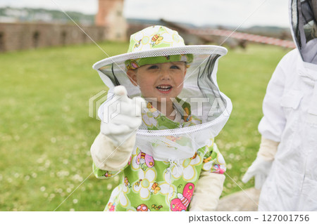 Beekeeper child in apiary in a protective suit 127001756