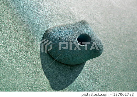 An artificial blue climbing hold on a wall. Close up 127001758
