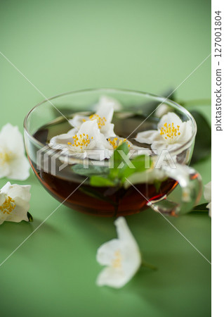 Fragrant jasmine tea in a glass container on a green background 127001804