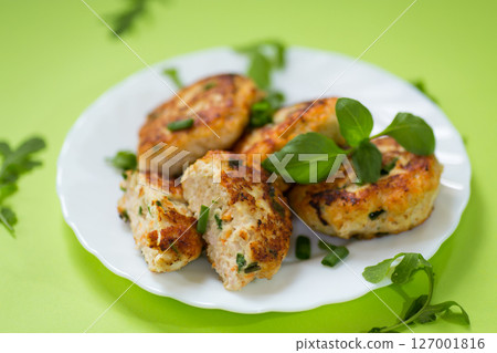 Homemade chicken cutlets on a plate isolated on a green background 127001816