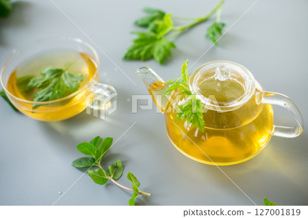 Tea in a glass teapot and cup with currant and mint leaves 127001819
