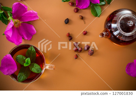 Top view of brewed rosehip tea with mint in glassware on brown background 127001830