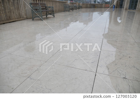 Wet marble floor in a courtyard after rain on a cloudy day 127003120