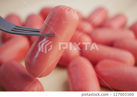 Preparing a forkful of sausages for a delicious meal 127003160