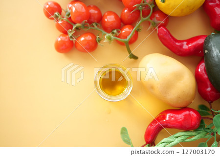 Fresh vegetables and olive oil arranged on a yellow background Fresh vegetables and olive oil arranged on a yellow background 127003170