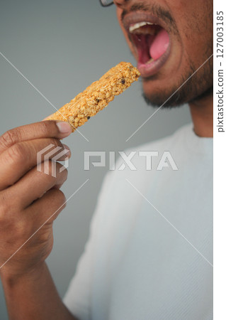 Person enjoying a granola bar in a casual setting 127003185