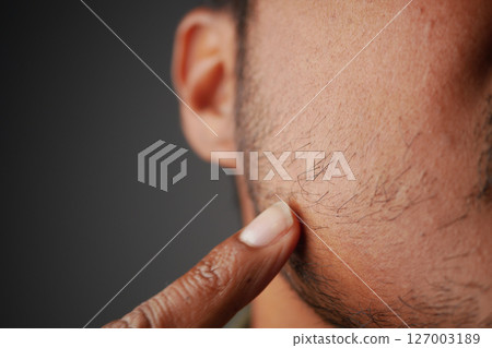 Close-up of a person's hand touching facial hair in natural light Close-up of a person's hand touching facial hair in natural light 127003189