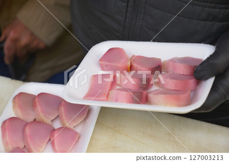 Fresh fish portions displayed on a white plate outdoors 127003213