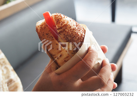 Delicious sandwich held by a hand in a casual setting Delicious sandwich held by a hand in a casual setting 127003232